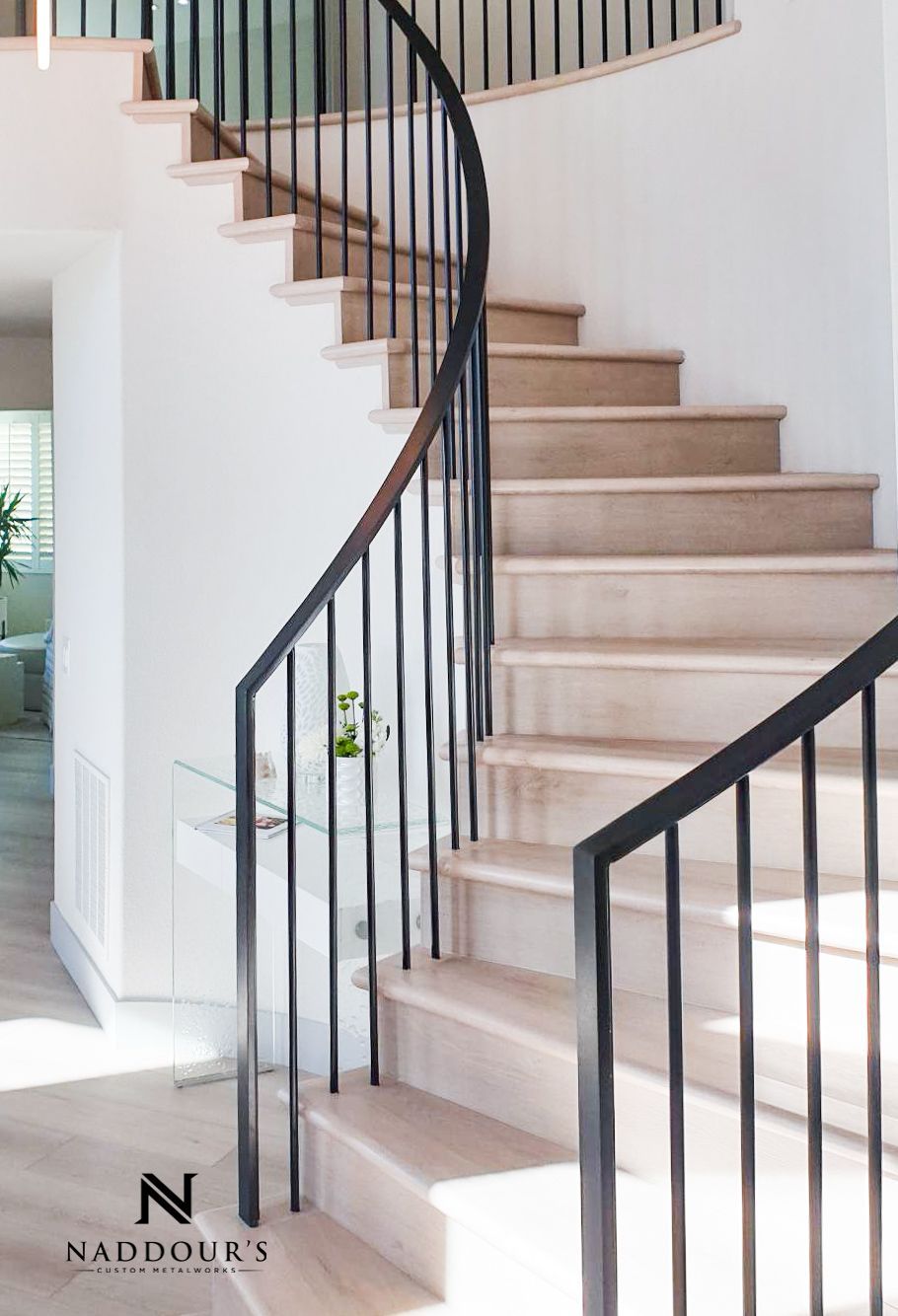 A curved staircase with a black railing in a house.