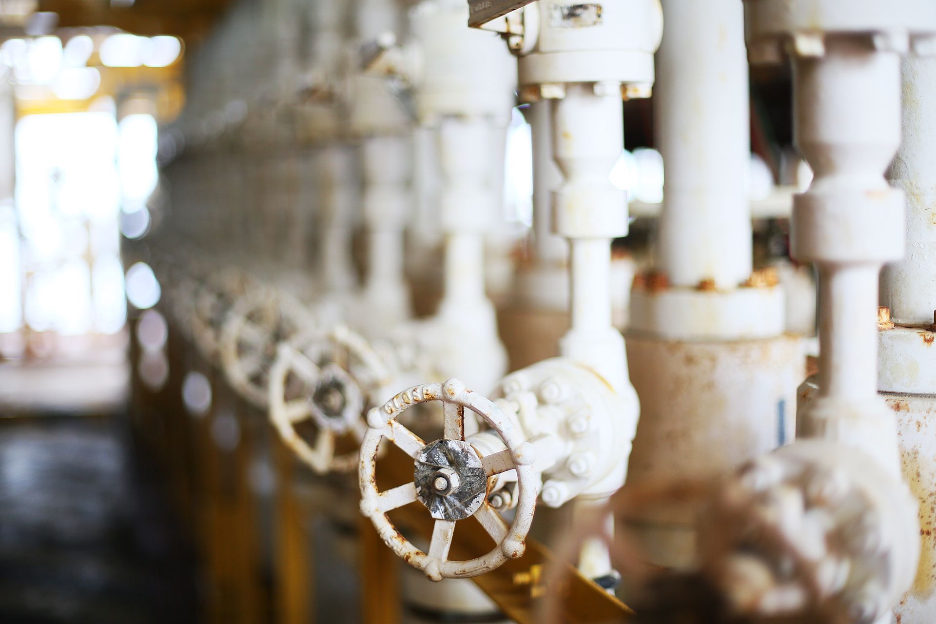 A row of white pipes and valves in a factory.
