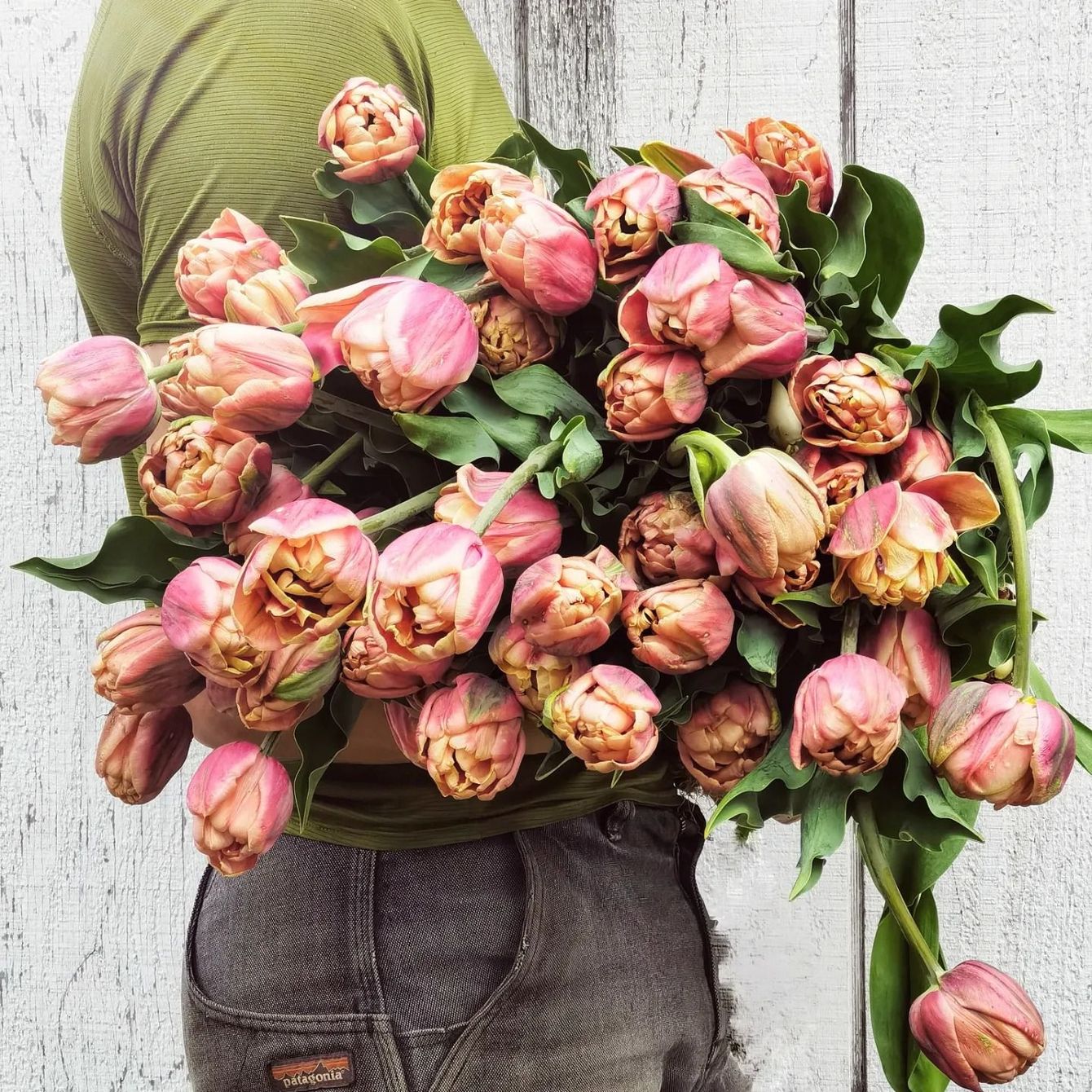 A person is holding a large bouquet of pink flowers