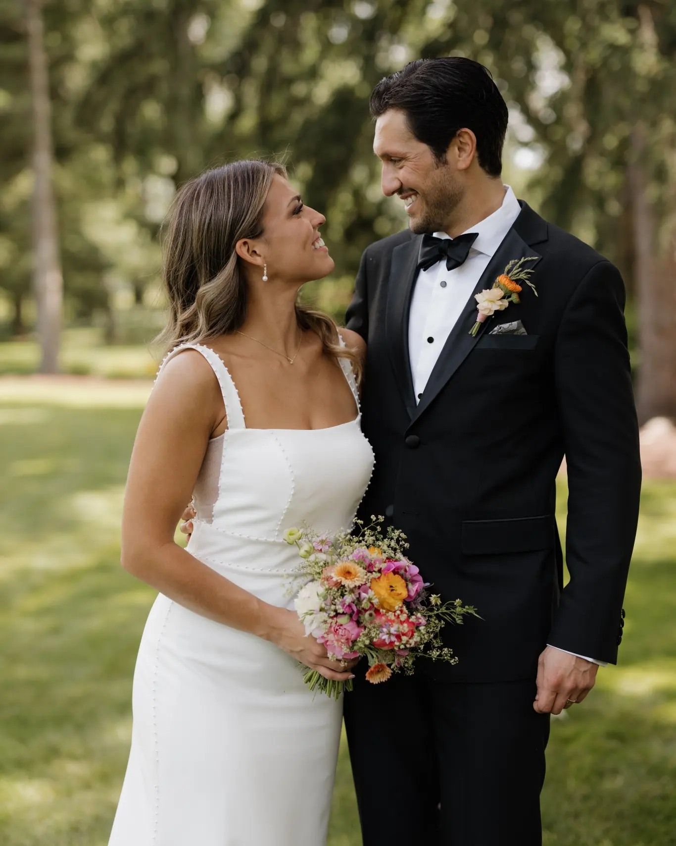 A bride and groom are posing for a picture in a park.