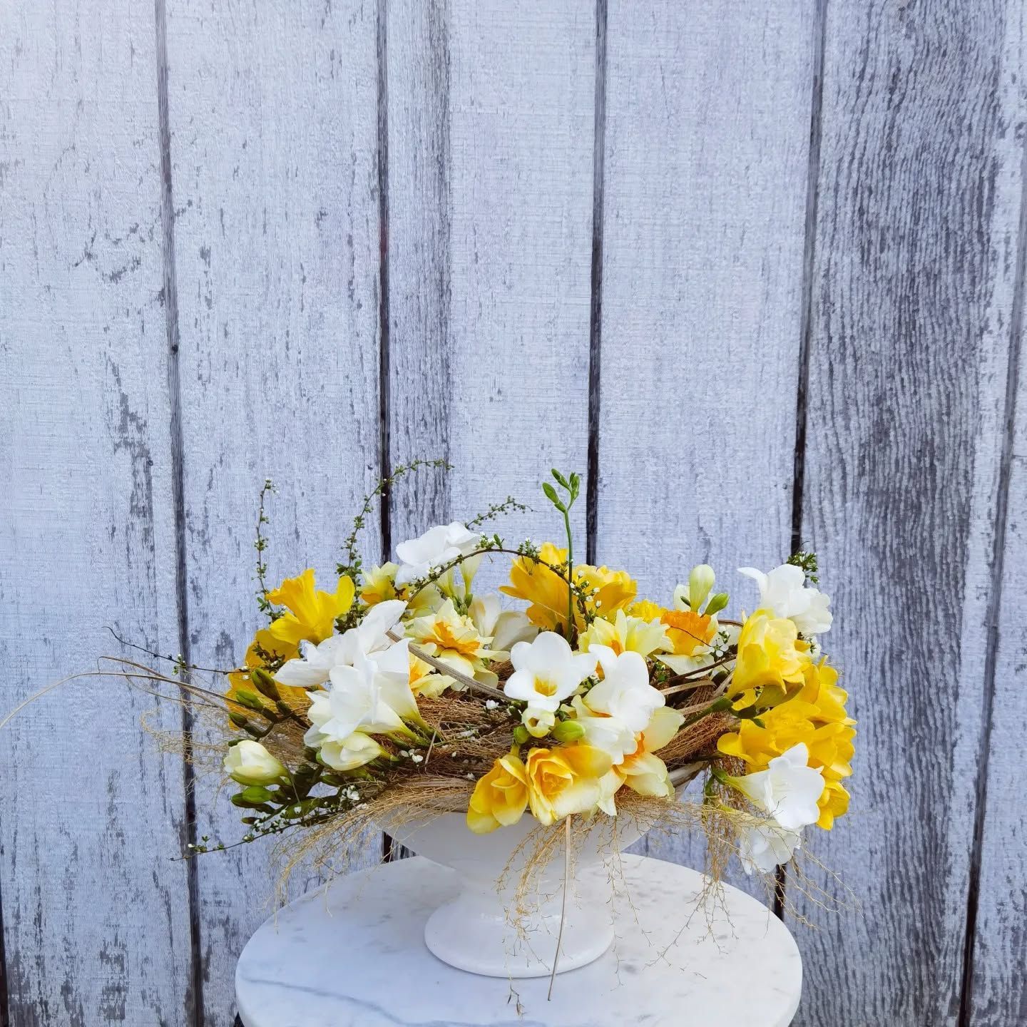 A white vase filled with yellow and white flowers