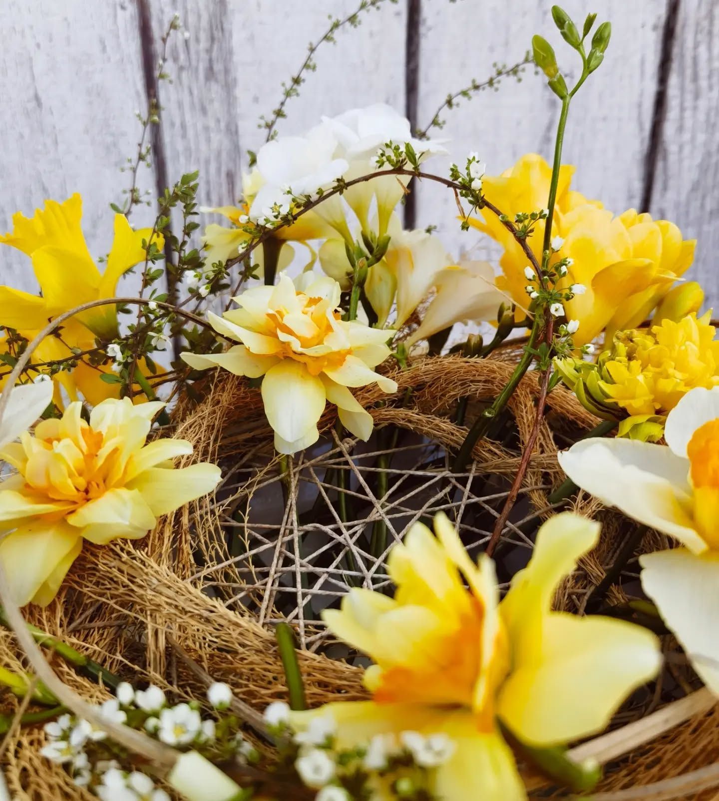 A bunch of yellow and white flowers in a basket