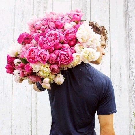 A man is carrying a large bouquet of pink and white flowers