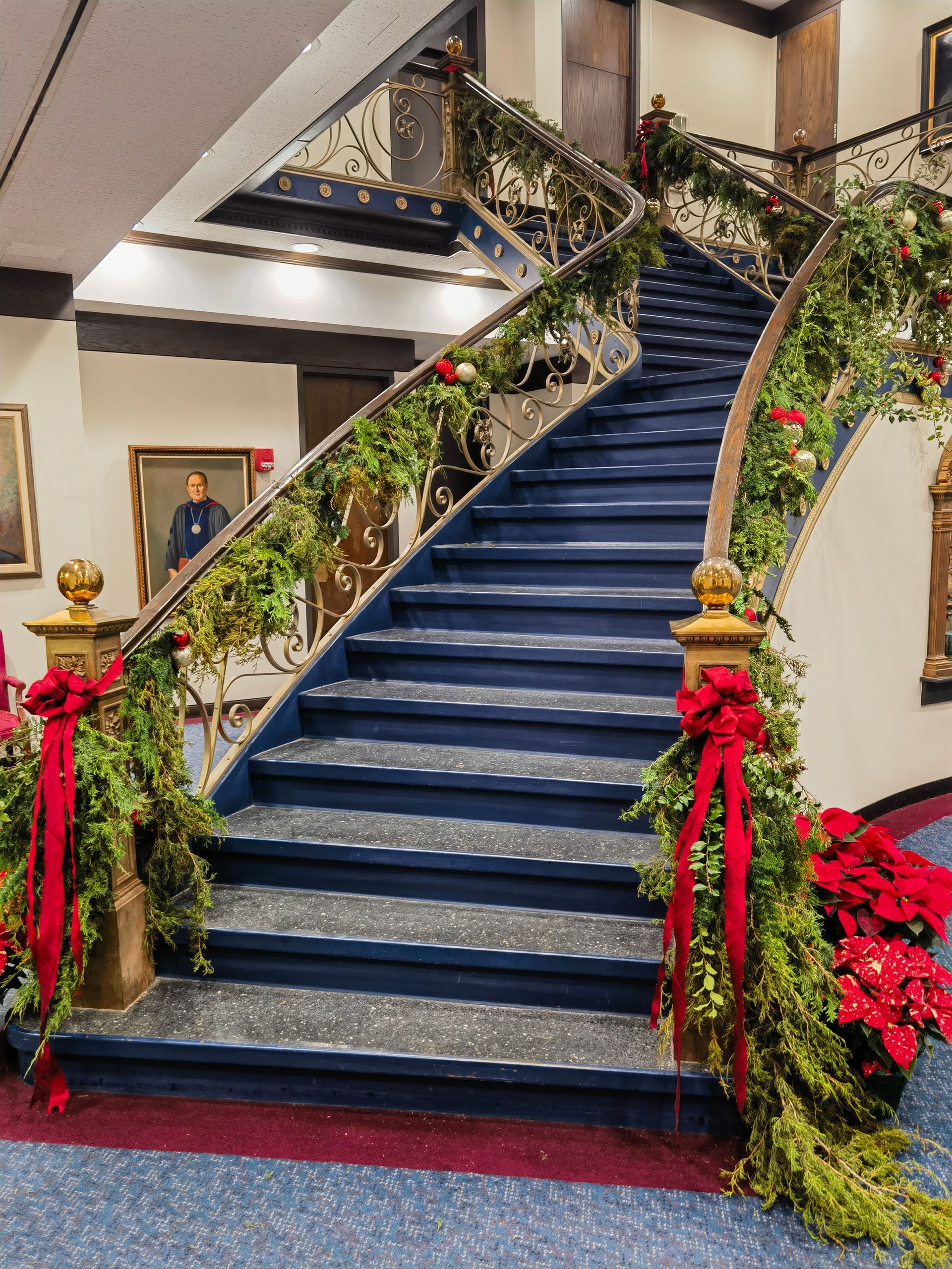A staircase decorated for christmas with red ribbons and greenery