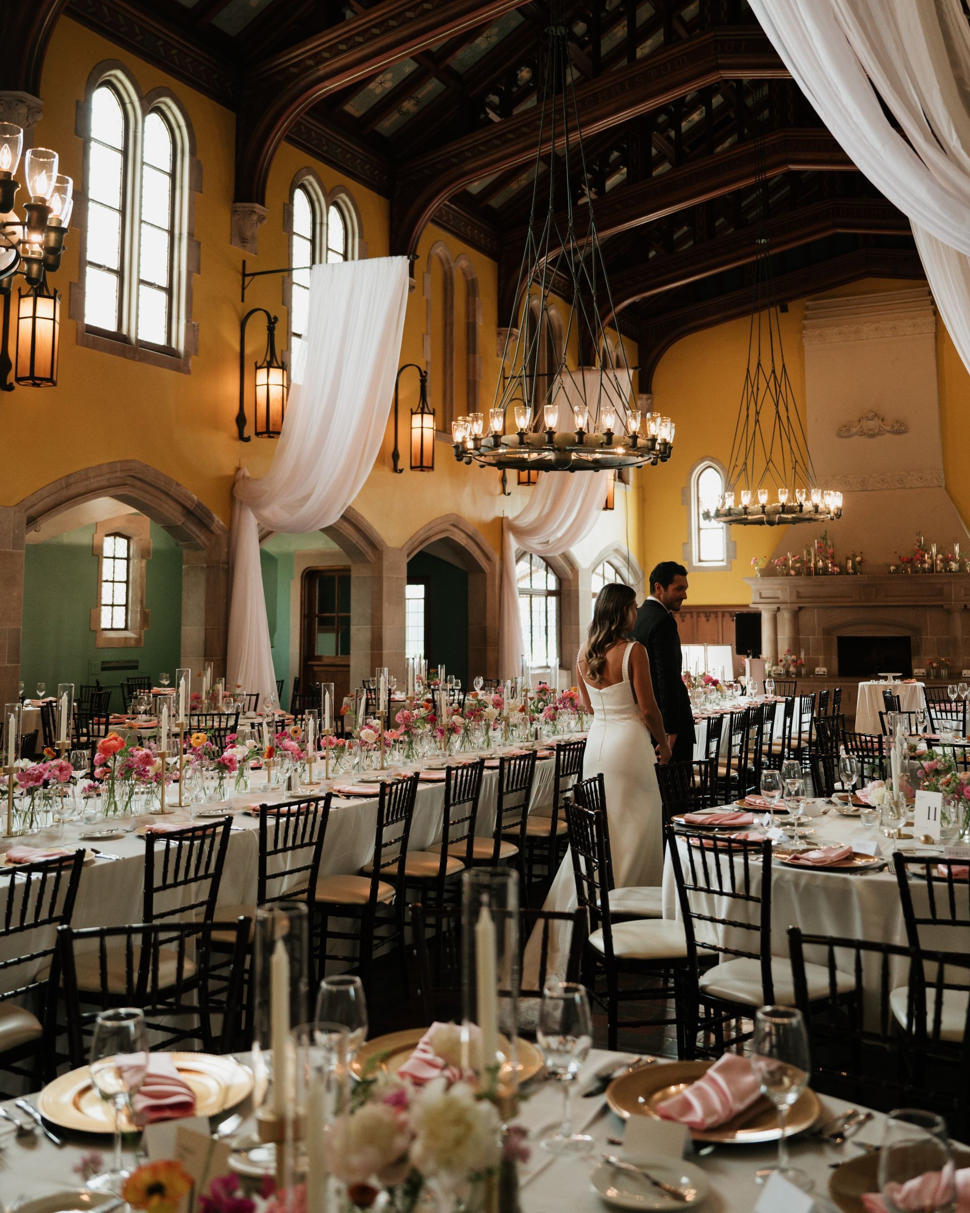 A large room with tables and chairs set up for a wedding reception