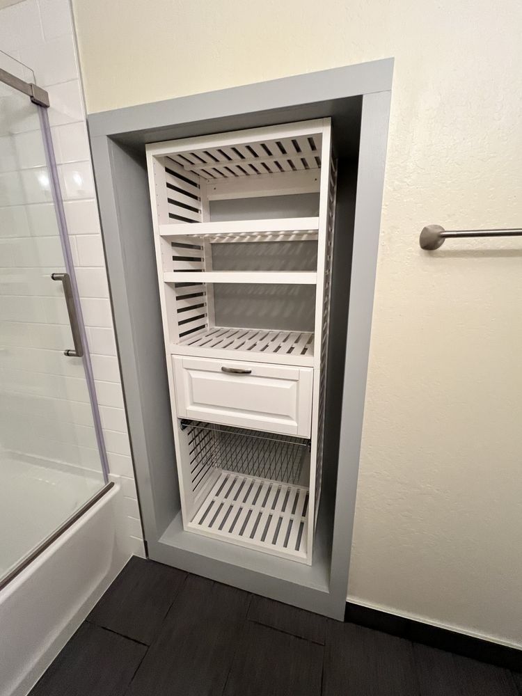Built-in white bathroom wall cabinet with shelves, drawers, and a vented door panel