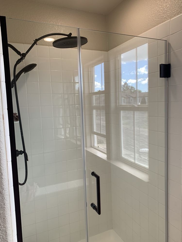 Glass shower enclosure with black hardware and white subway tile walls in a bright bathroom
