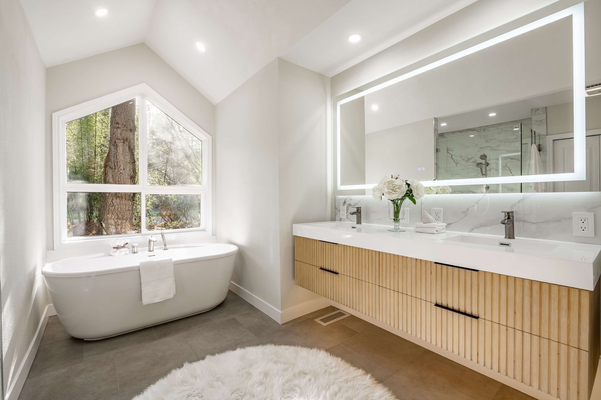 Bright modern bathroom with a freestanding tub, double vanity, and large mirror.