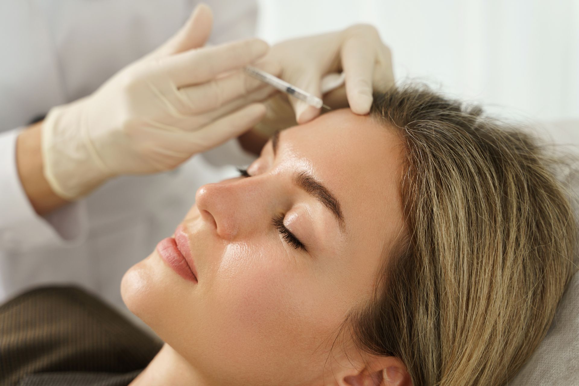Woman receiving facial injection from gloved hands.