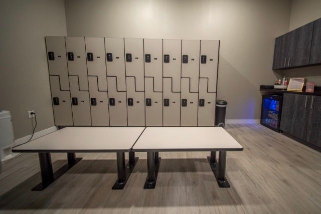 Modern locker room with beige lockers, two benches, and dark cabinets on the right.