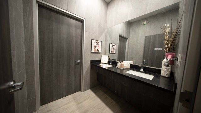 Modern restroom with dark wood doors, gray walls, and a black countertop with sink and decor.