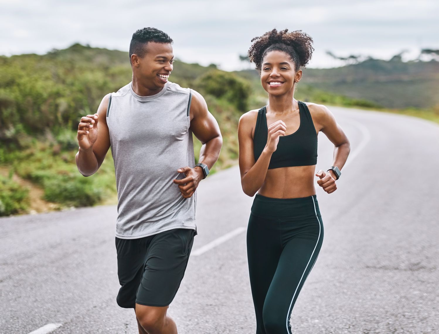 A man and a woman are jogging on a road.