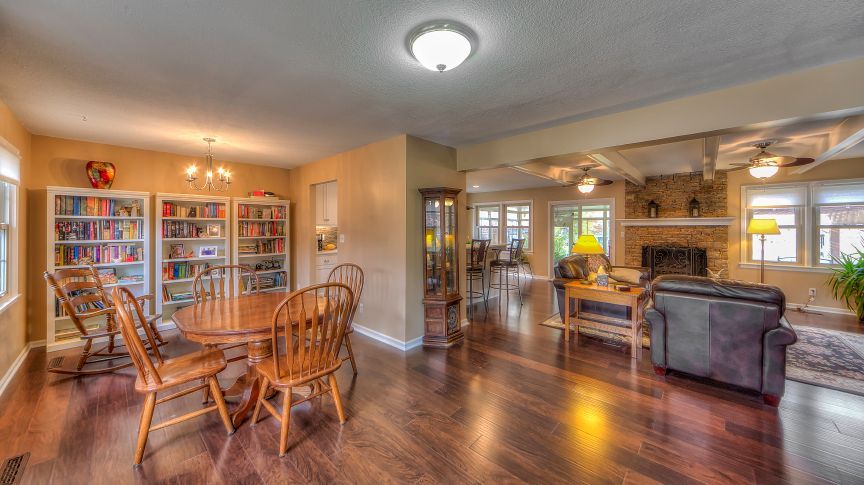 Open-concept living space with a dining area, built-in bookshelves, and a cozy den with a stone fireplace.