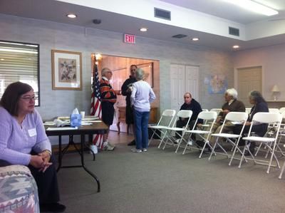 A group of people are gathered in a room with an exit sign