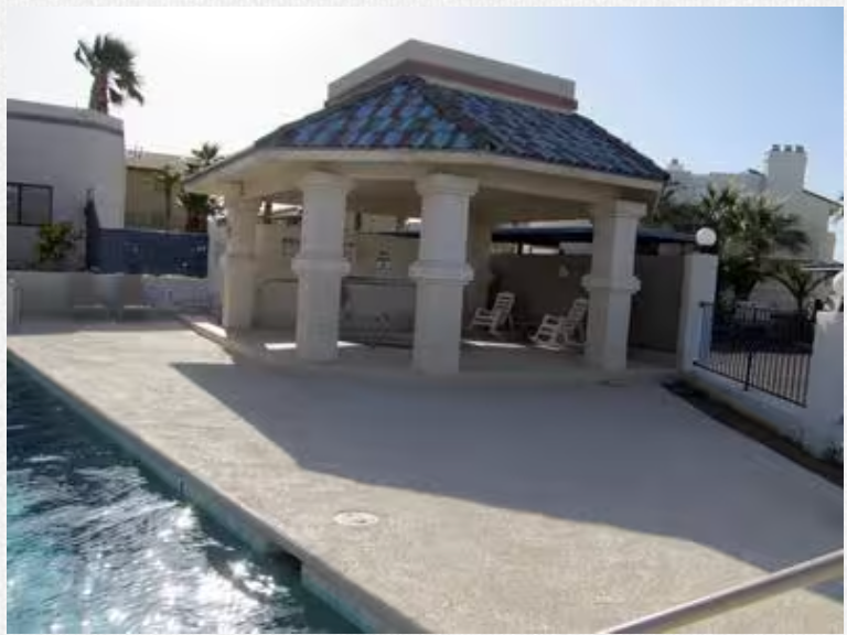 A gazebo with a blue roof sits next to a swimming pool