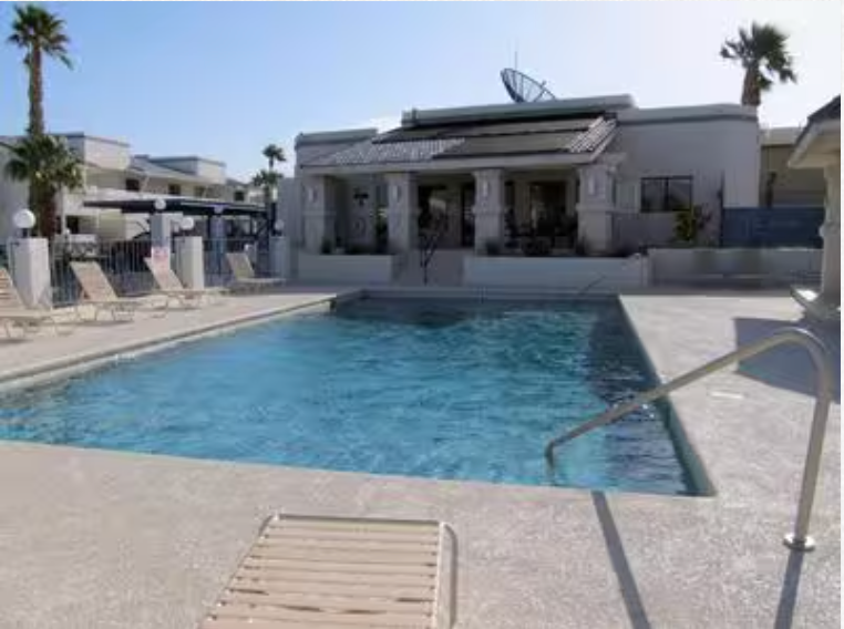 A large swimming pool in front of a house with palm trees