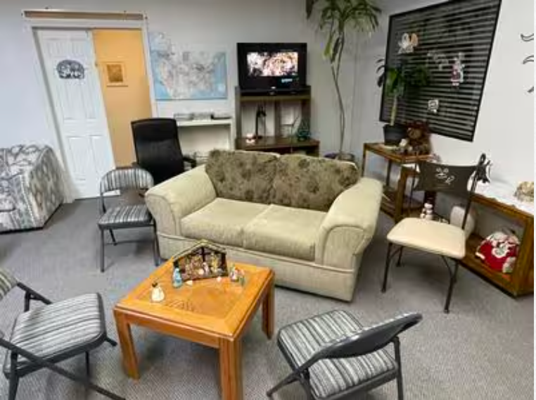 A living room with a couch , chairs , a table and a television.