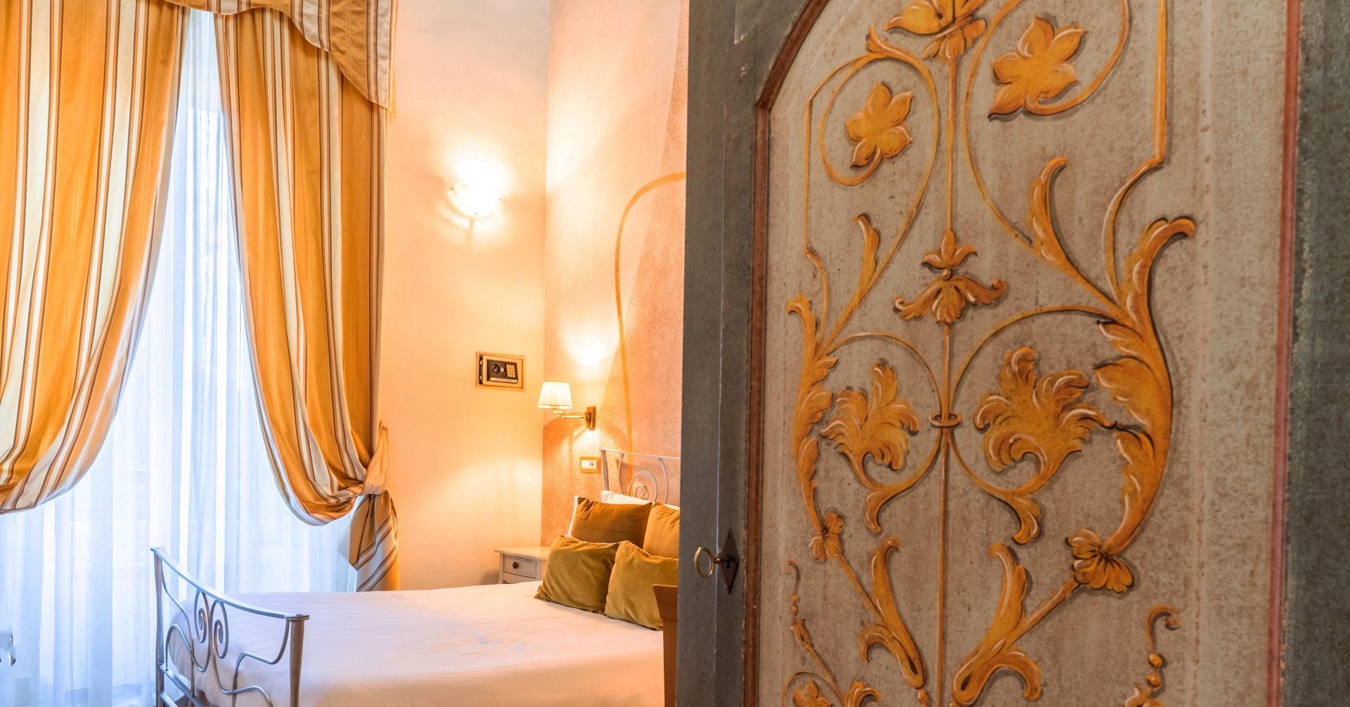 The door is open to a bedroom with a bed and curtains.
