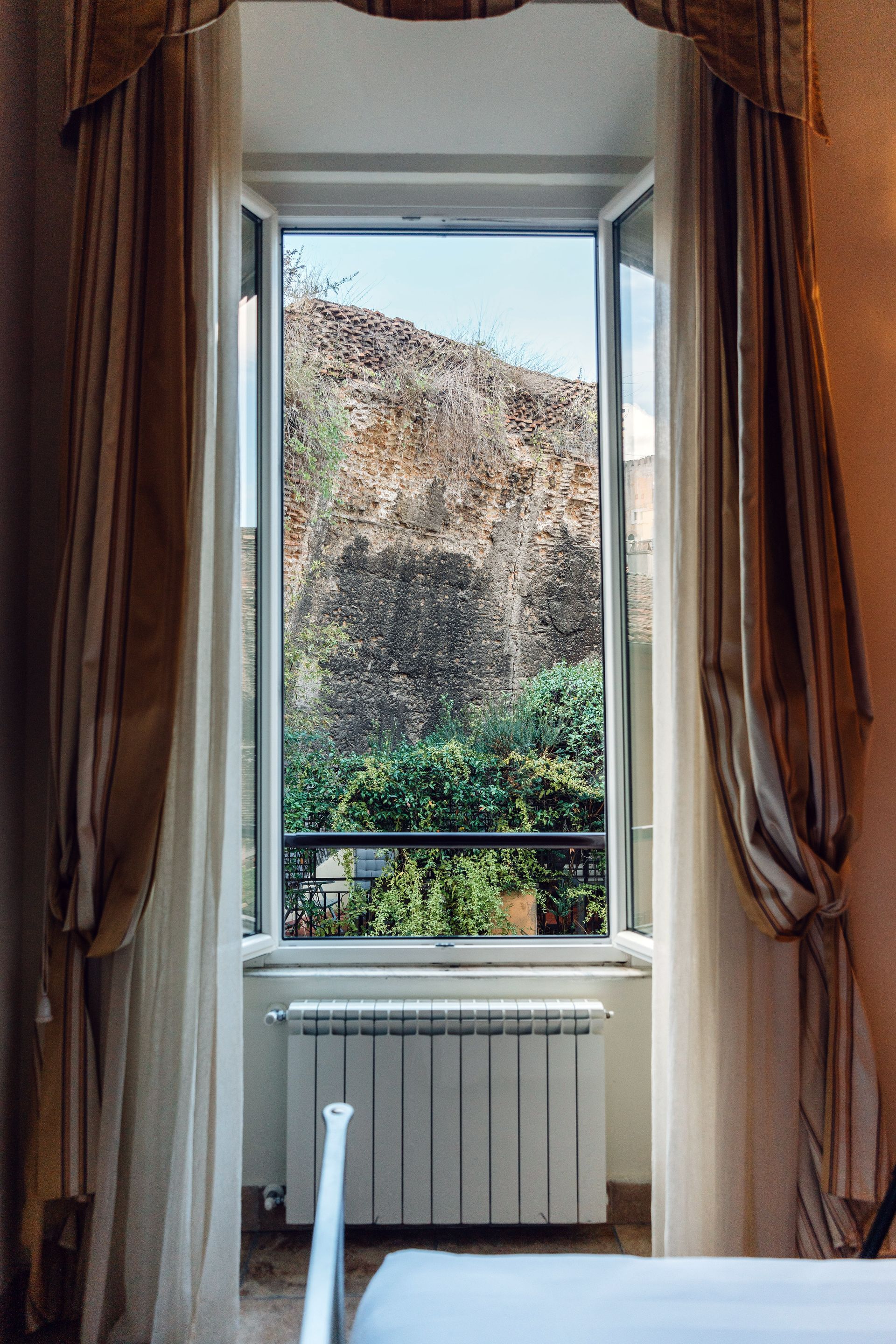 A bedroom with a bed and a window with a view of a balcony.