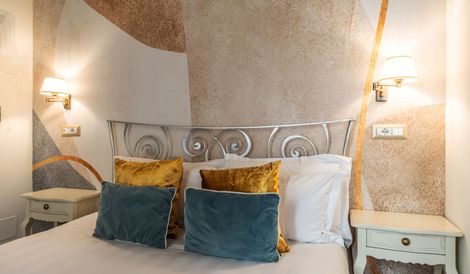 A bedroom with a bed , nightstand , and lamp.