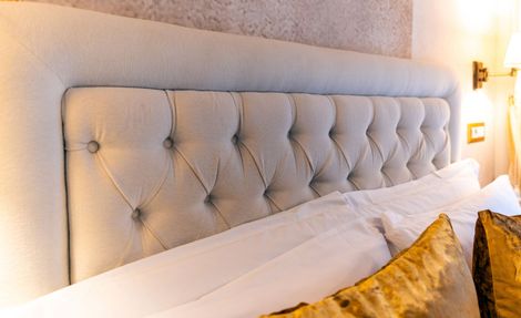 A bed with a tufted headboard and pillows in a hotel room.