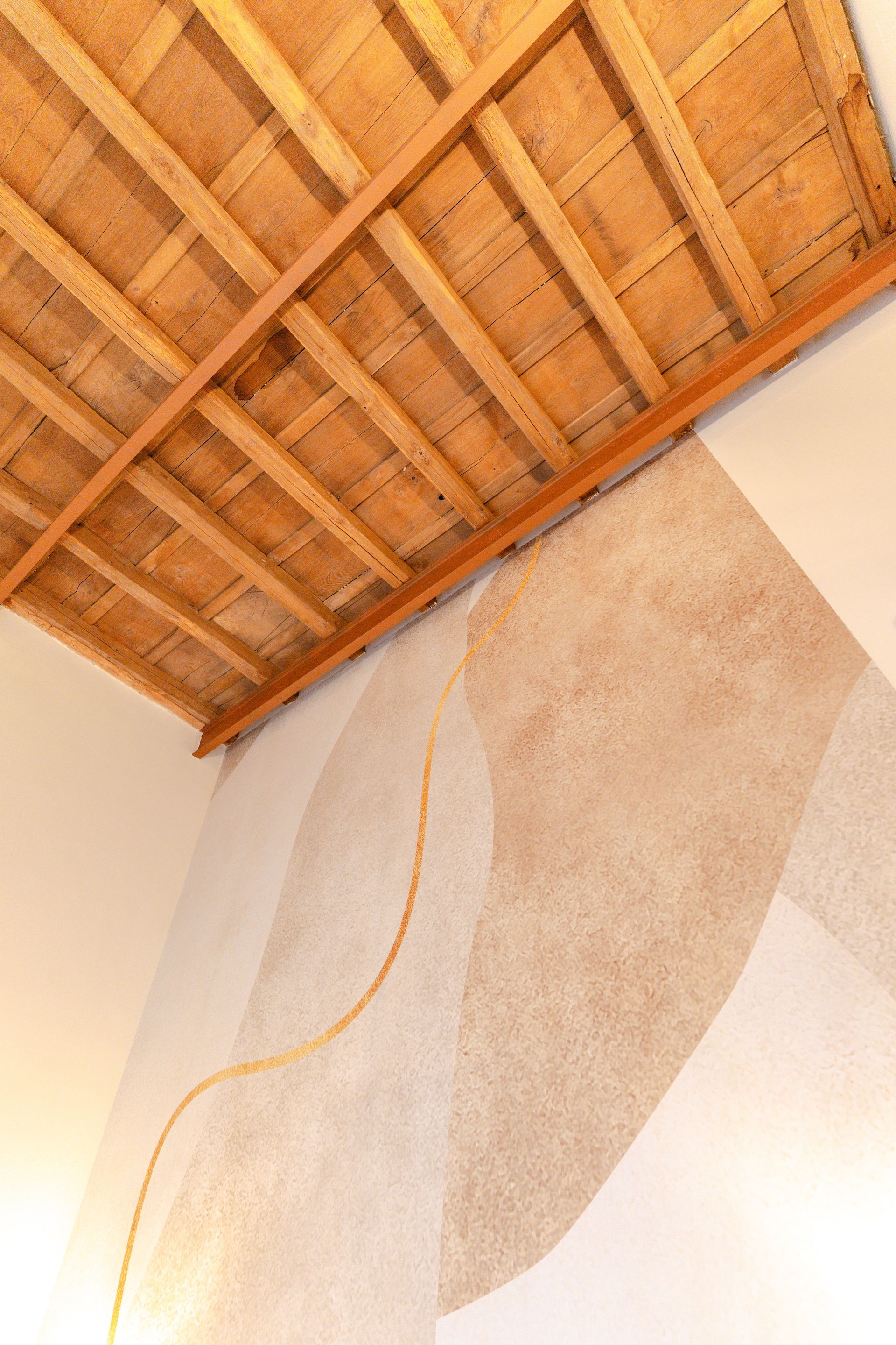 A room with a wooden ceiling and a painting on the wall.