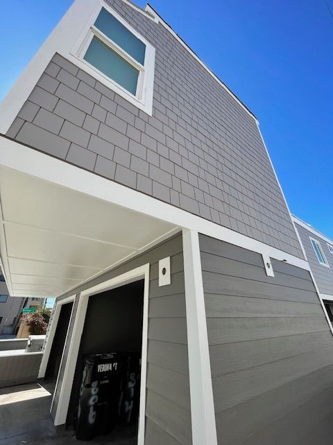 Modern gray house exterior with white trim and a small upper window, viewed from below