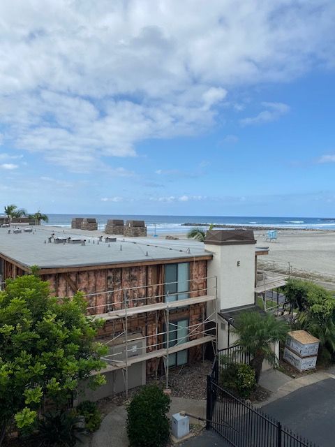 Coastal building beside a sandy beach and ocean under a cloudy blue sky