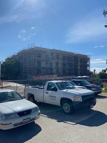 Parking lot with white pickup truck in front of a large building under construction on a sunny day