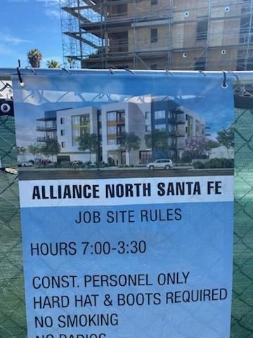 Construction site sign for Alliance North Santa Fe, listing job site rules and hours behind a fence.