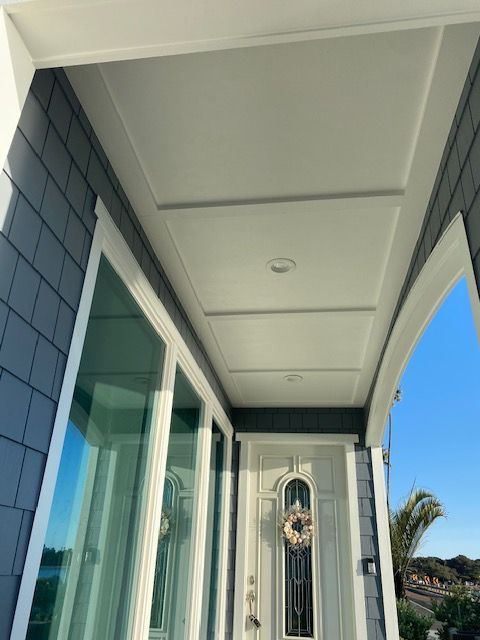 Front porch with white ceiling panels, blue siding, glass door, and decorative front door view.