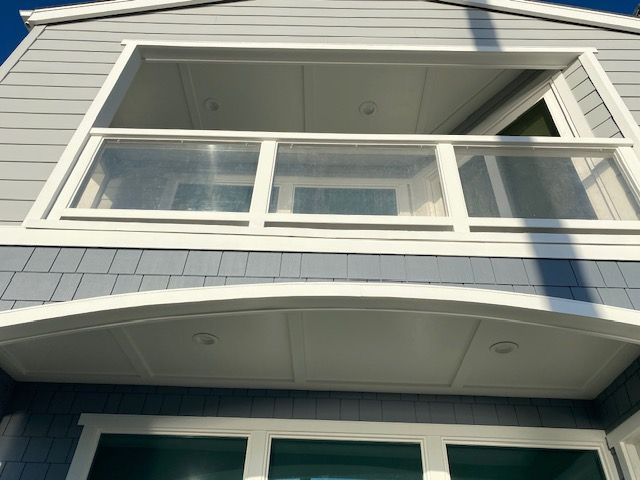 White house balcony with large windows and a gray exterior facade