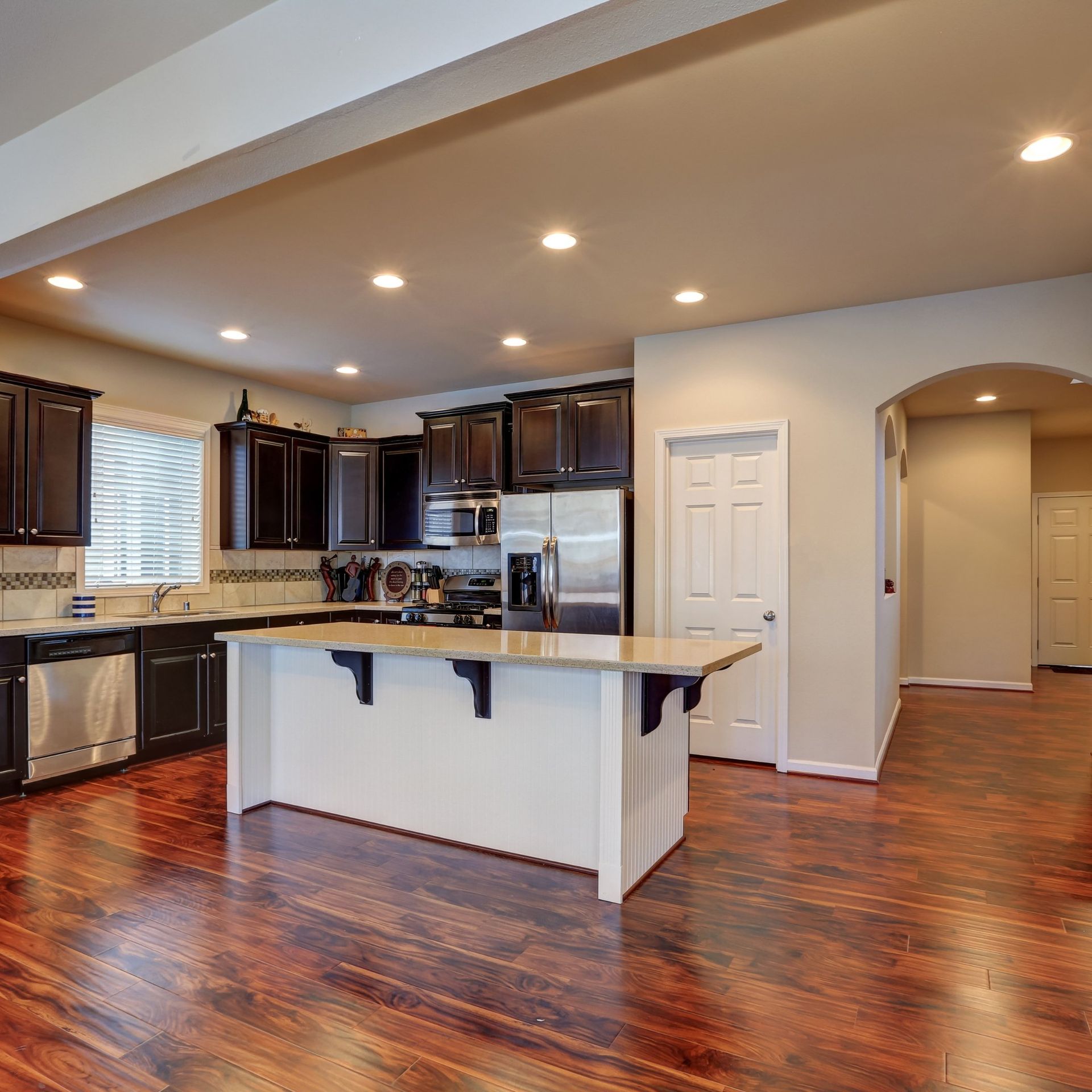 Modern kitchen with dark wood cabinets, stainless appliances, island, and hardwood floors