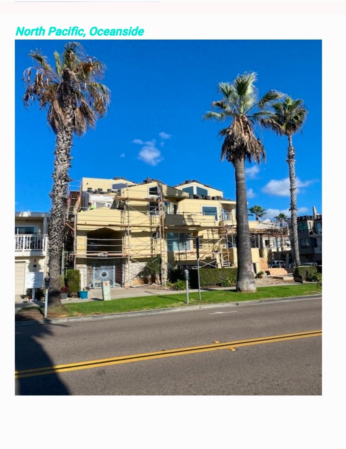 Sunny street view of a beige apartment building with palm trees and a blue sky in Oceanside, California