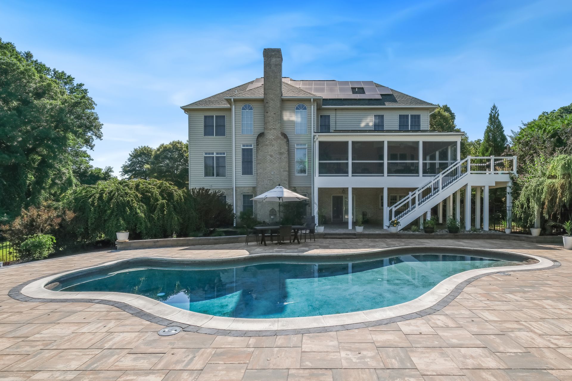 Large house with a pool and patio in a sunny backyard
