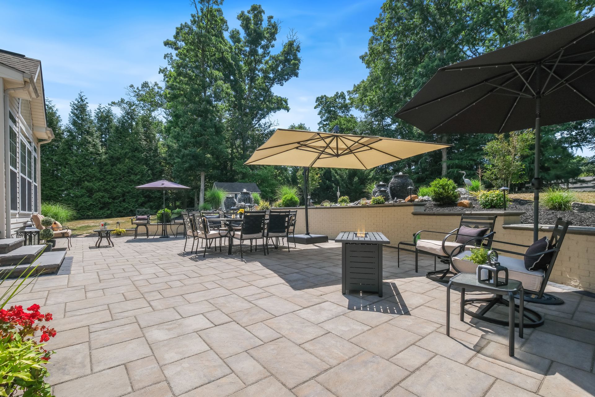 Patio with tables, chairs, umbrellas, and potted flowers on a sunny terrace