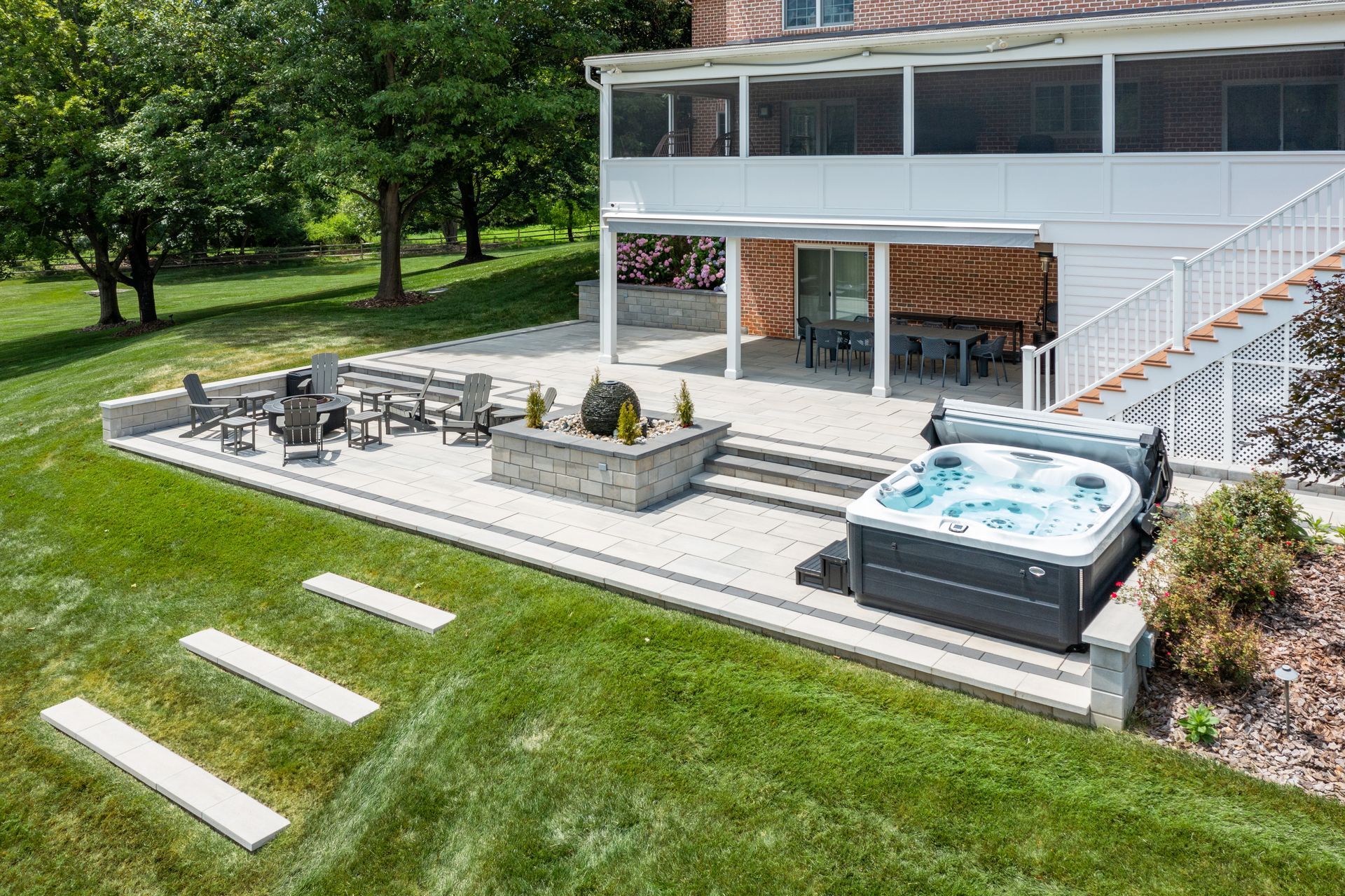 Modern white house patio with outdoor seating, hot tub, stairs, and lawn steps