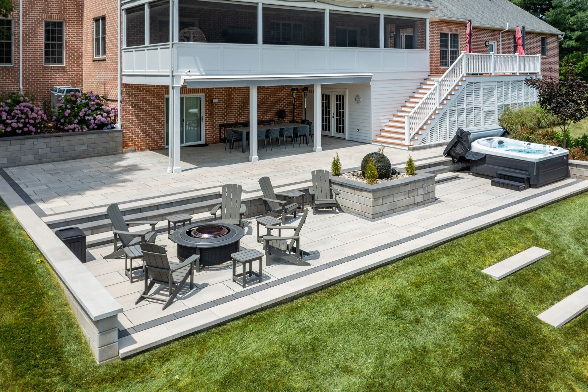 Backyard patio with outdoor seating, raised planter, and hot tub beside a brick house