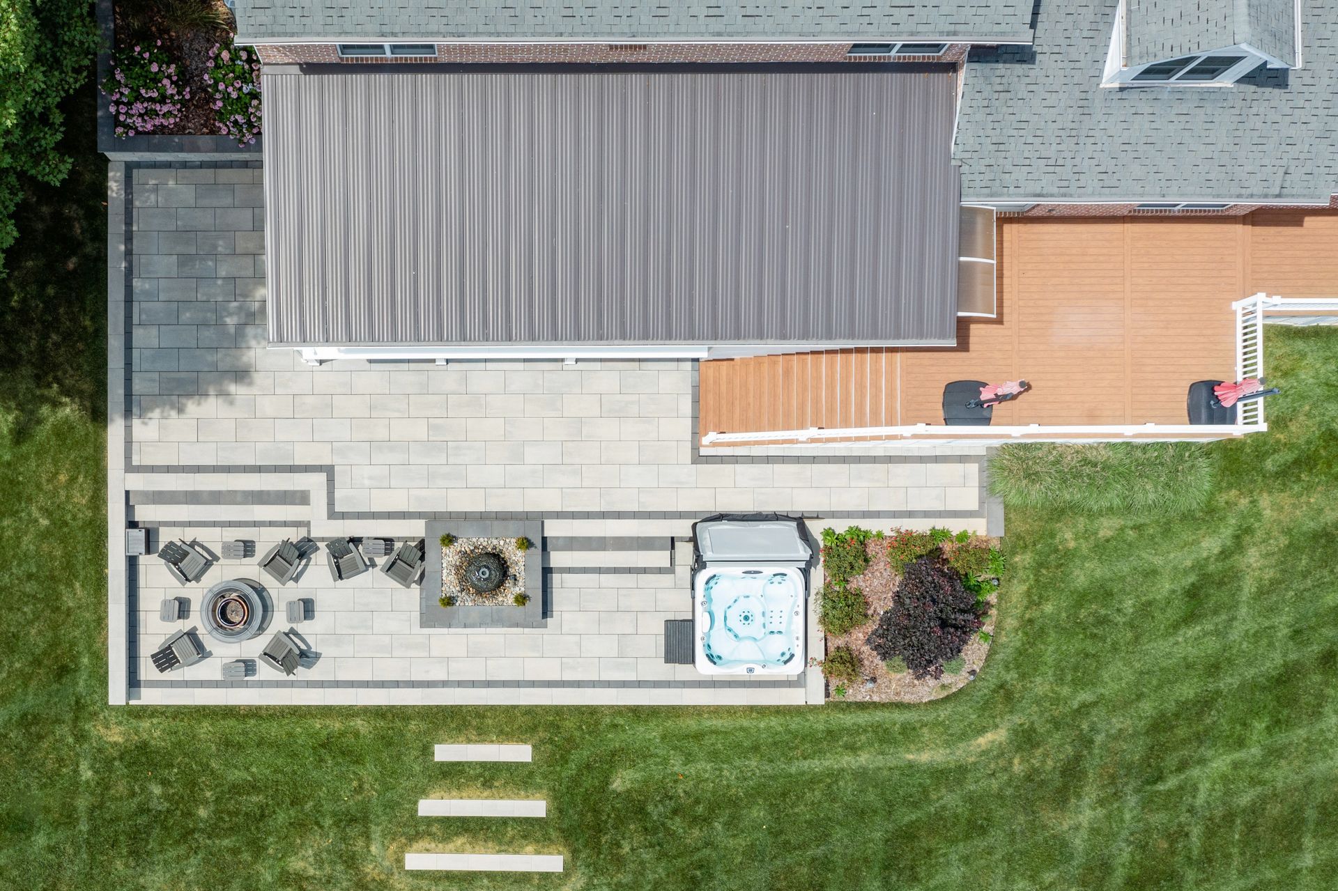 Aerial view of a house patio with pavers, outdoor furniture, and a grassy yard.