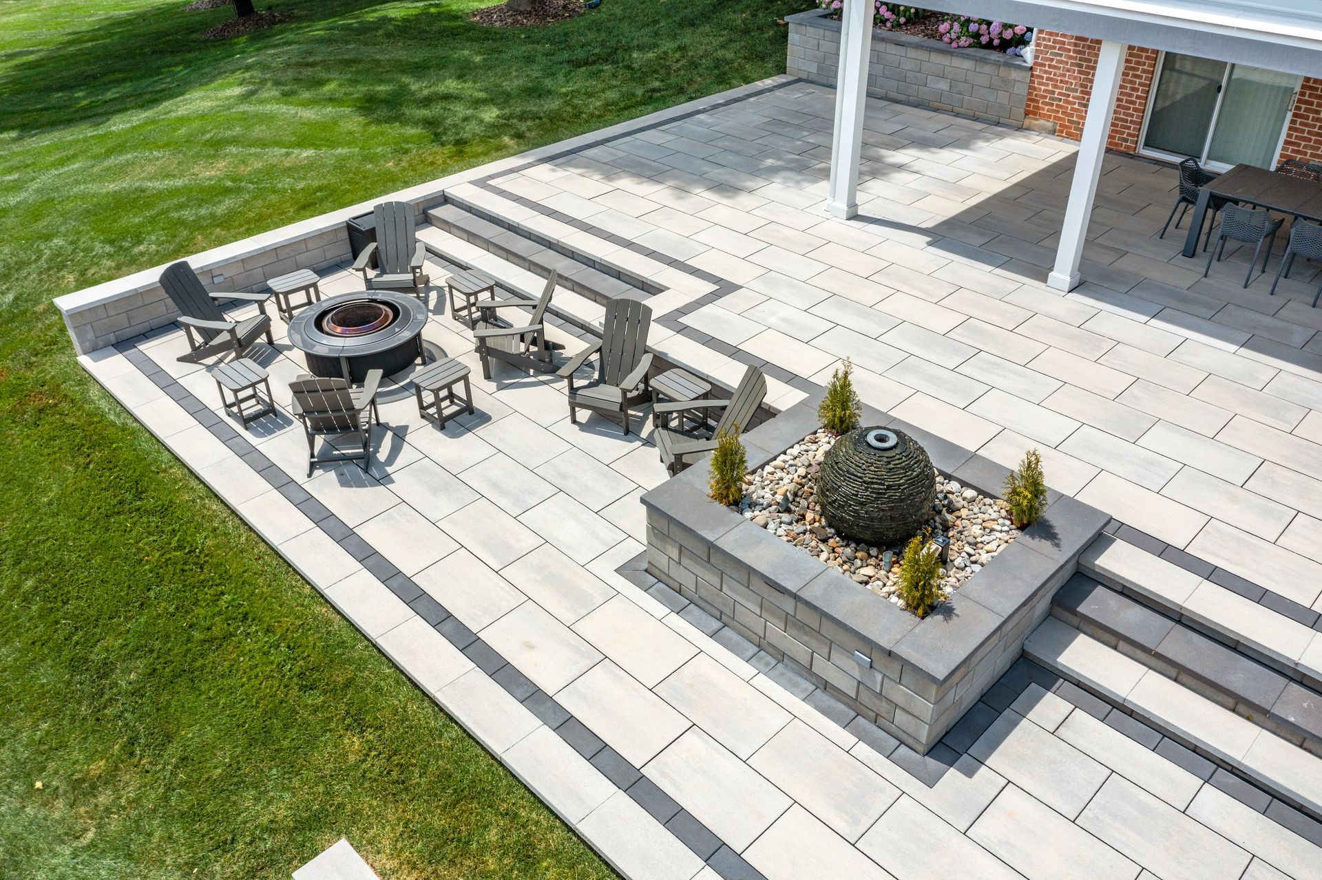 Outdoor patio with fire pit seating, stone steps, and a raised planter beside a lawn