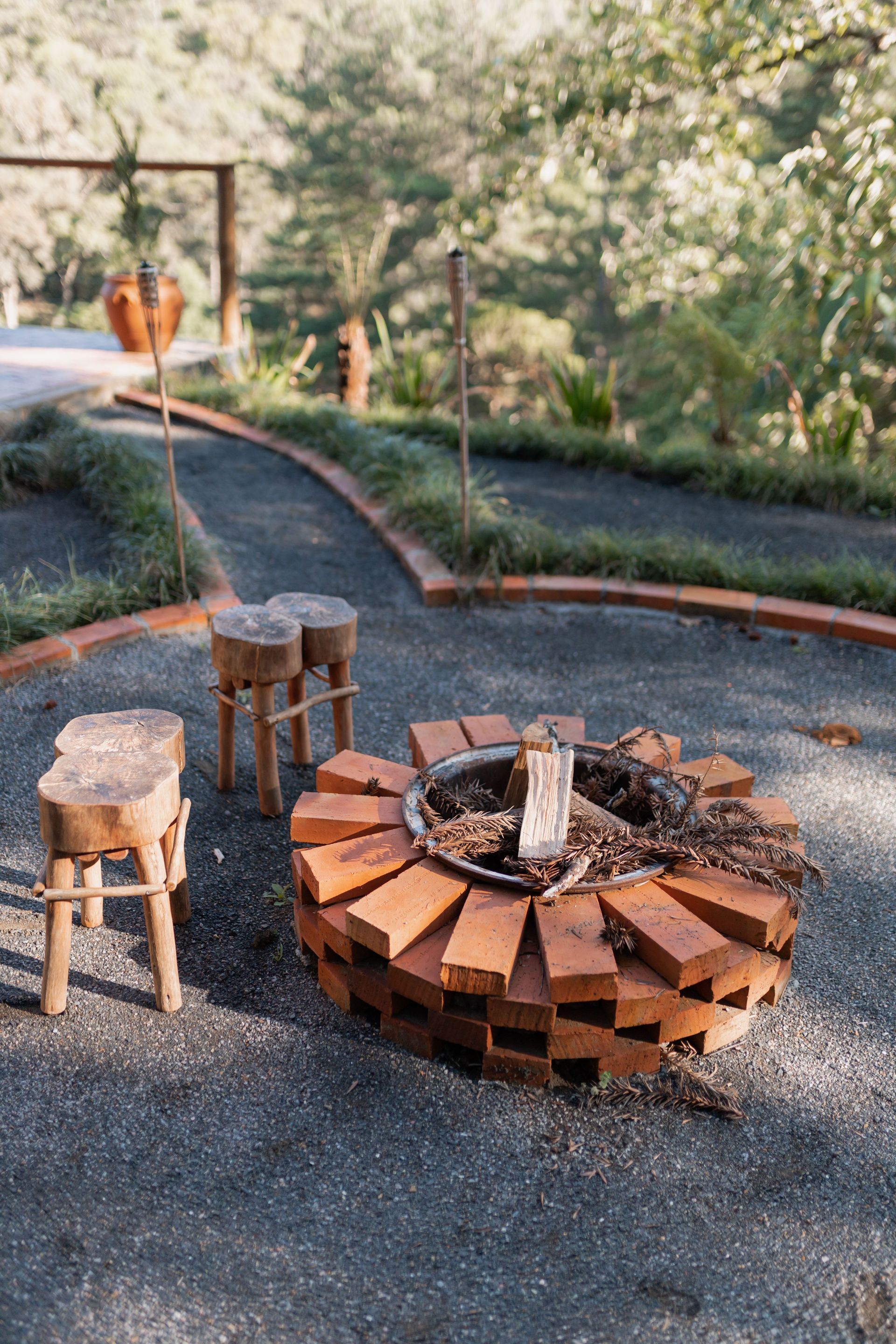 Patio with white chairs, red umbrella, and stone fire pit in a grassy backyard