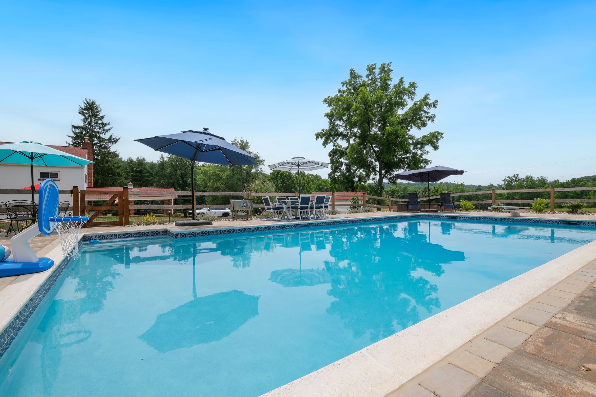Outdoor swimming pool with blue water, lounge chairs, and umbrellas under a clear sky