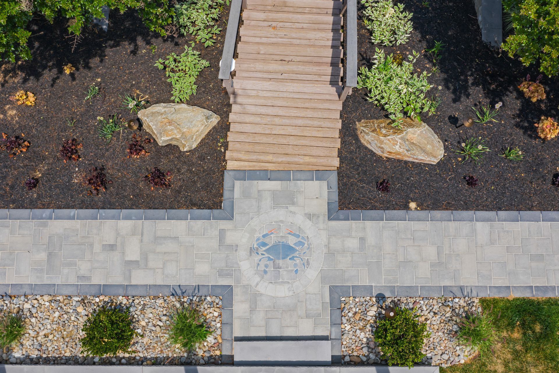 Top-down view of a landscaped walkway with steps, stone pavers, and small shrubs.
