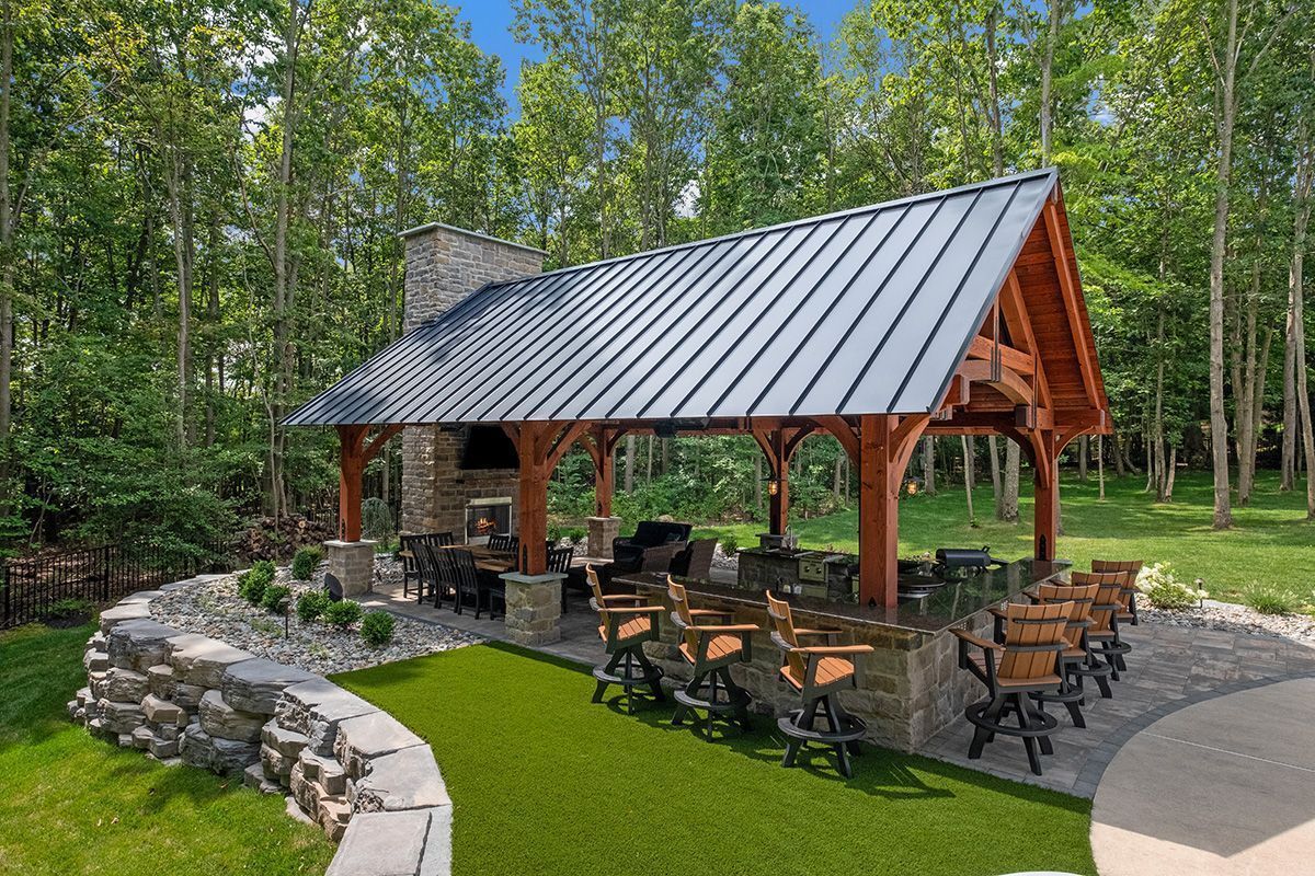 Covered outdoor pavilion with picnic tables and fire pit in a wooded park