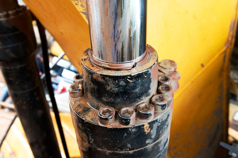 Close Up of A Chrome Hydraulic Piston Rod and Bolted Black Cylinder with Rust — NQBC Pty Ltd in Bowen, QLD