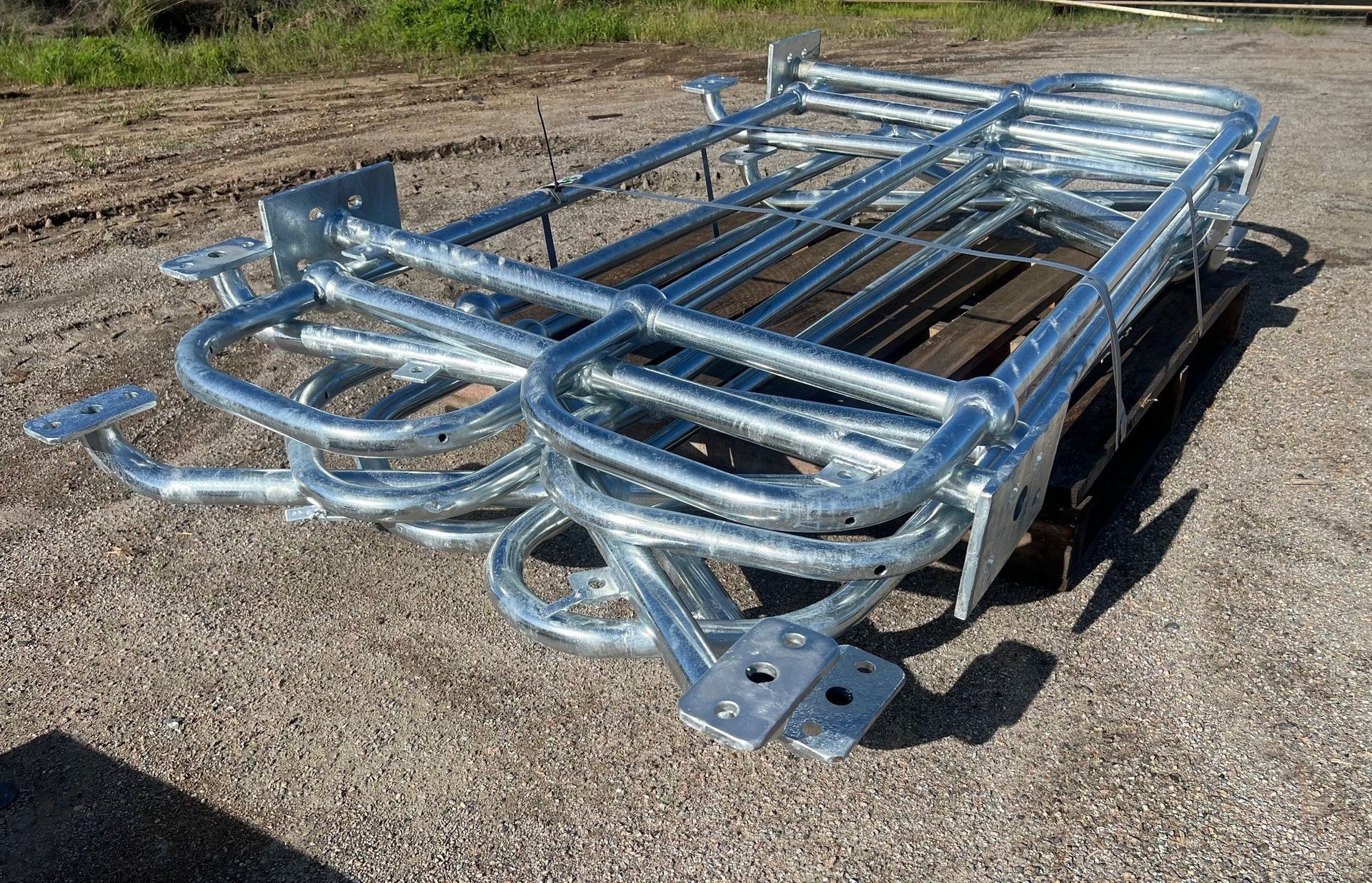 Silver metal livestock trailer frame on gravel, with curved rails and hitch plate outdoors