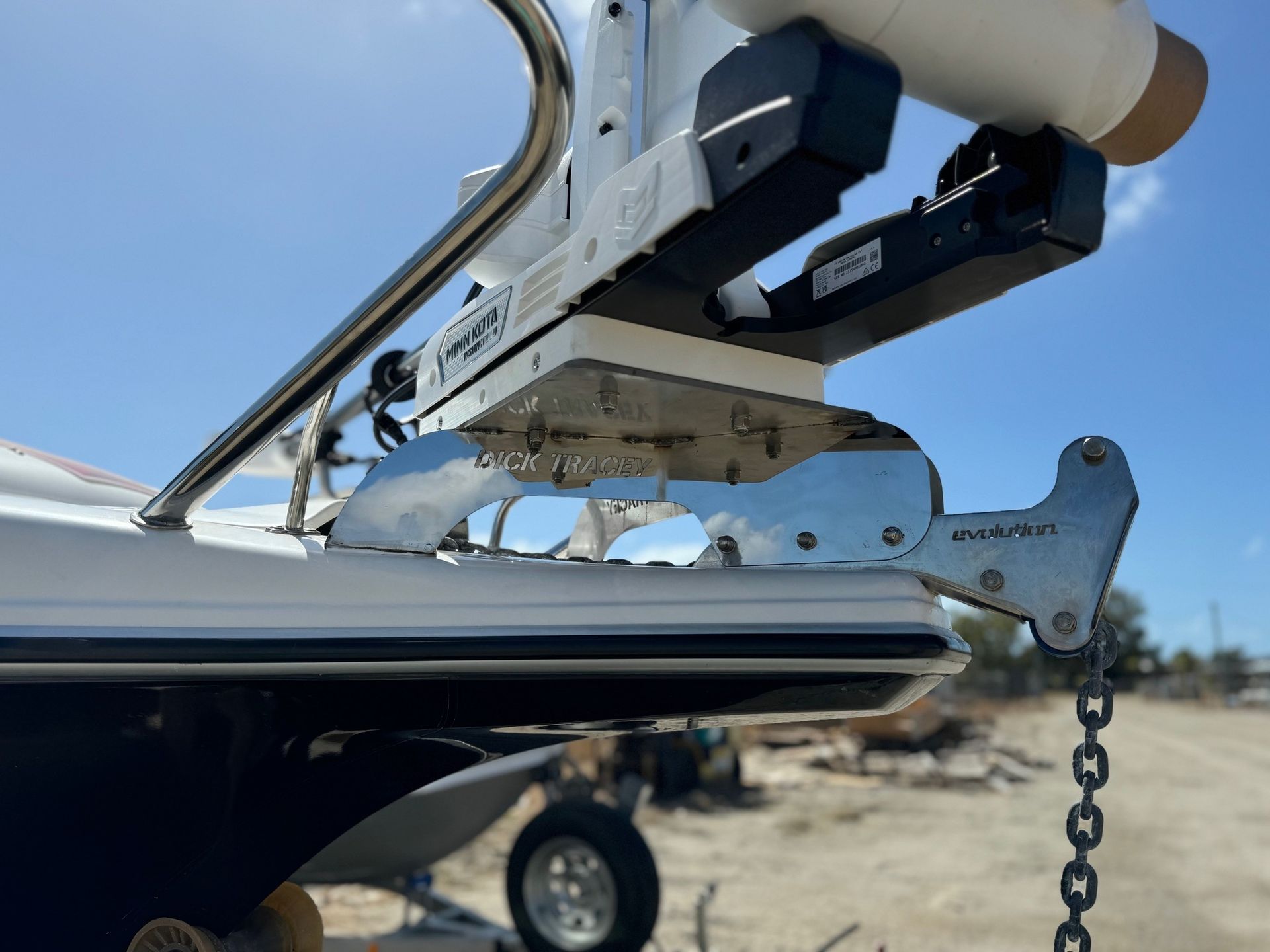 Boat trailer hitch and winch assembly attached to the bow of a white boat under a blue sky