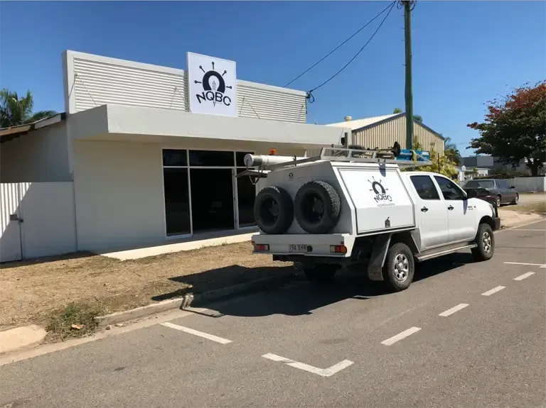 A White Truck is Parked on the Side of the Road in Front of a Building — NQBC Pty Ltd in Bowen, QLD