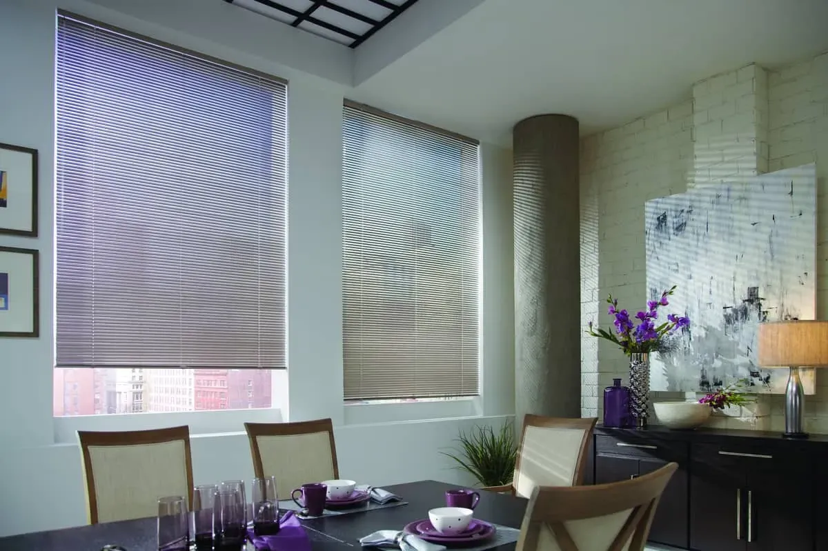 Dining room with pleated window shades; table set for dining, and artwork.
