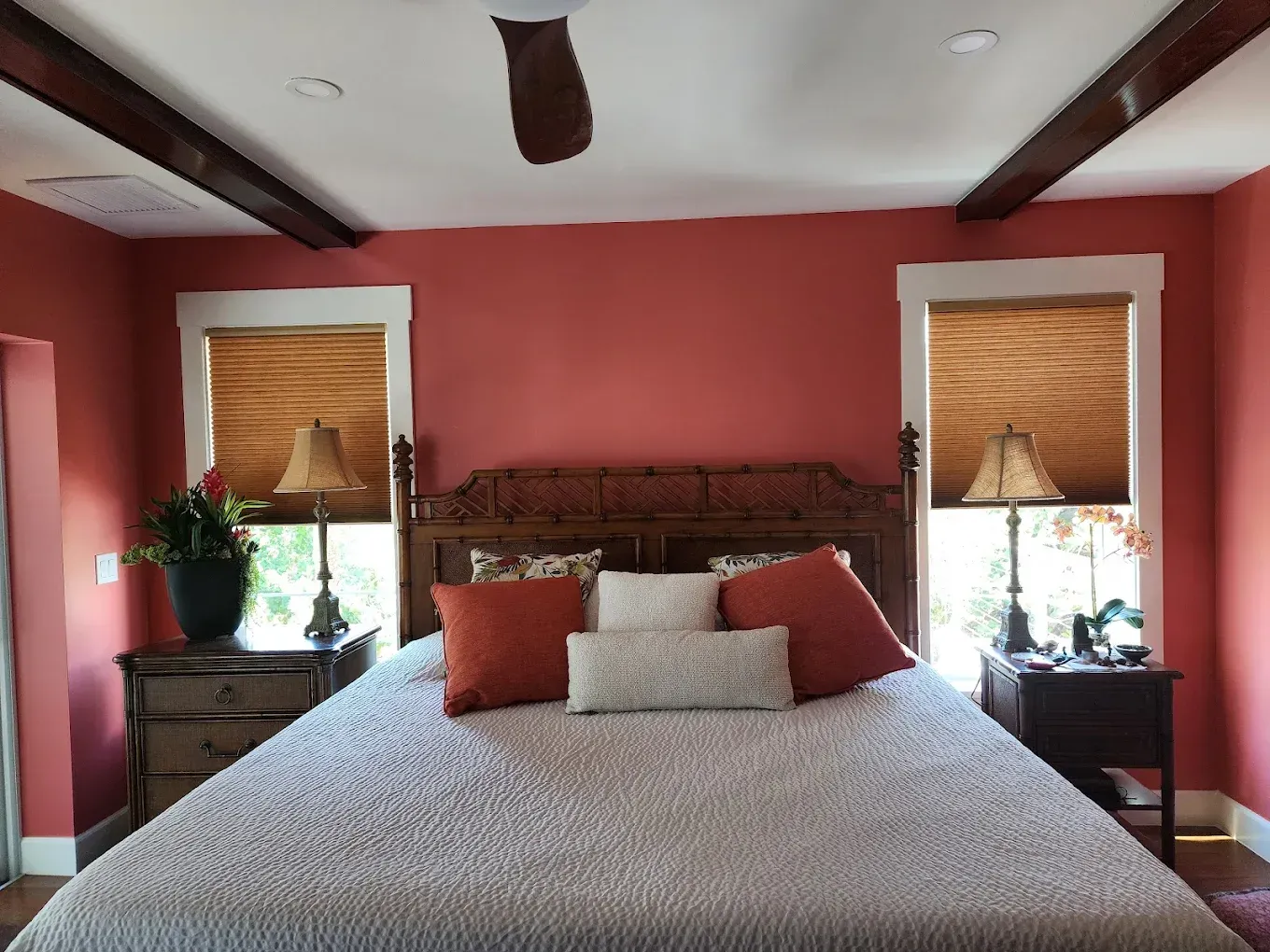 Bedroom with coral walls, wooden bed frame, two nightstands, and beige bedding.